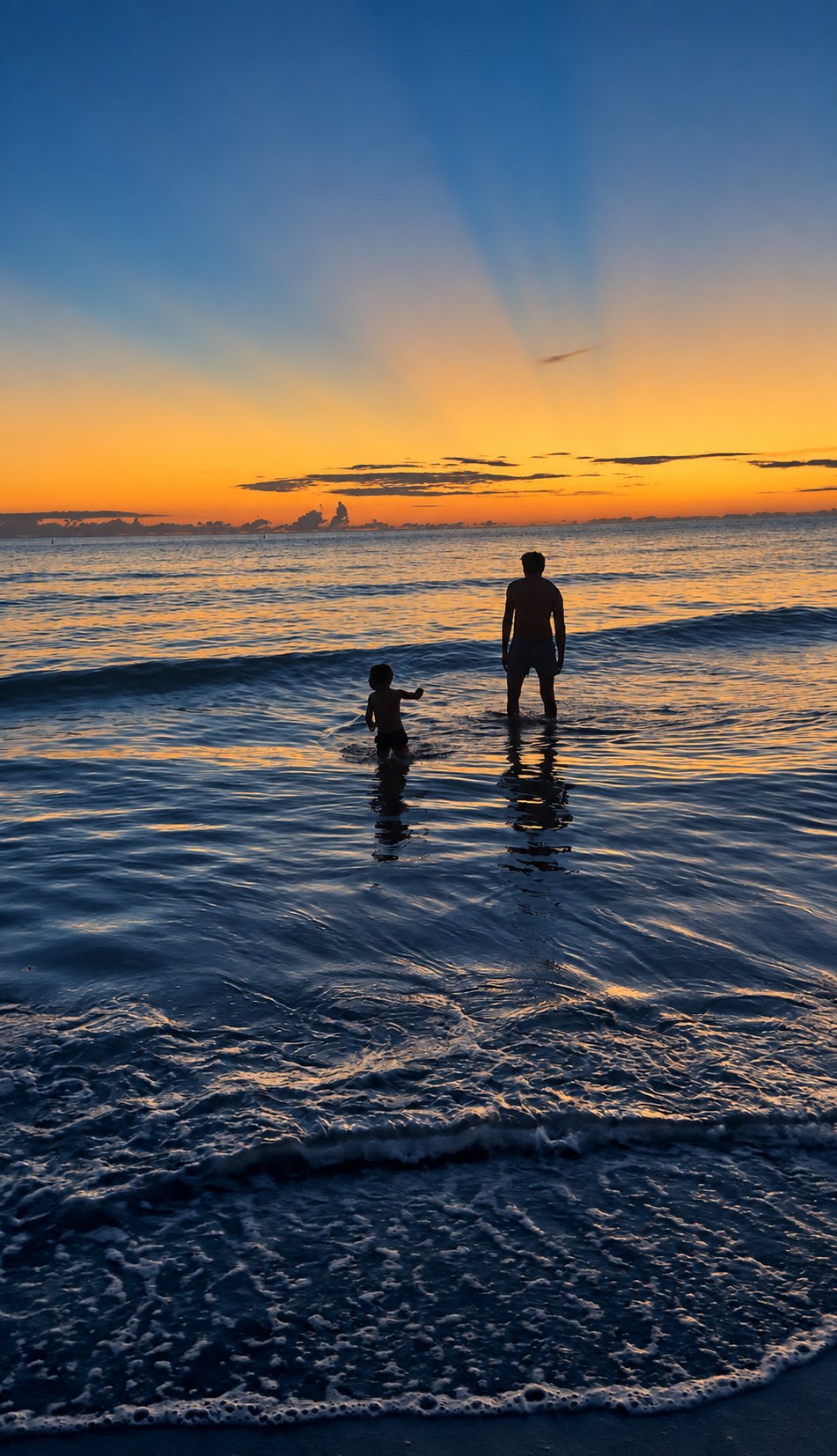 Sunset on Sunset Beach, Treasure Island: a father and child in the Gulf at dusk